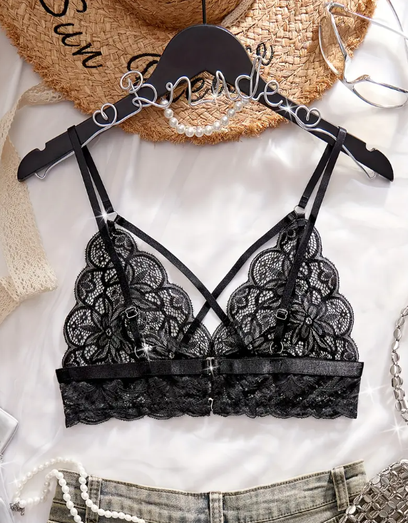 Black lace bra by The Seventh Muse on a hanger with a straw hat and jeans in the background
