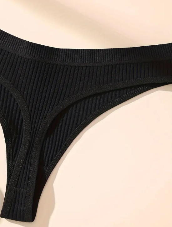 Set of five black seamless ribbed thong panties.