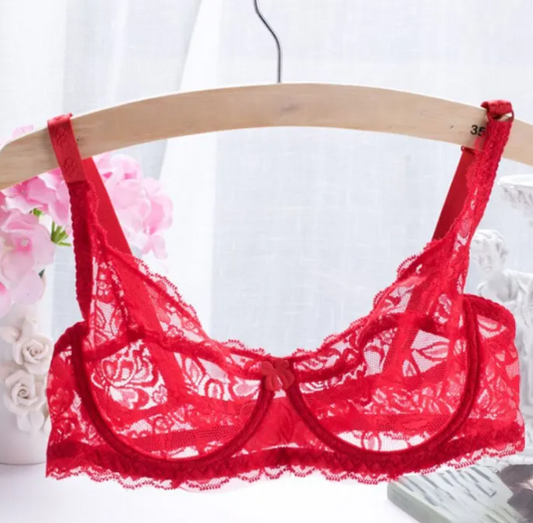 A red sheer lace underwire bra displayed on a wooden hanger, with floral lace detailing and adjustable straps.