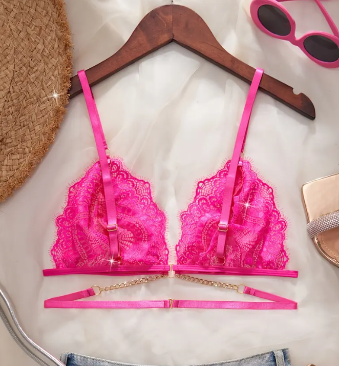 Close-up of a vibrant hot pink sheer lace bralette featuring a deep plunge, thin adjustable straps, and a decorative gold chain below the cups.