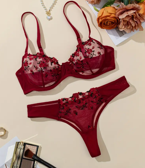 Red floral lingerie set on a beige surface with flowers and jewelry in the background
