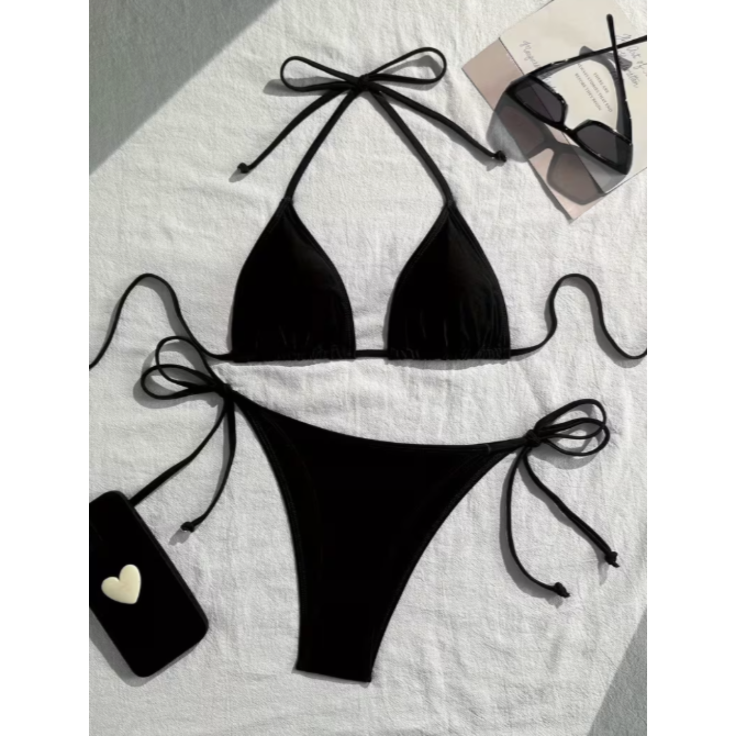 Black bikini set with bow details on a light background