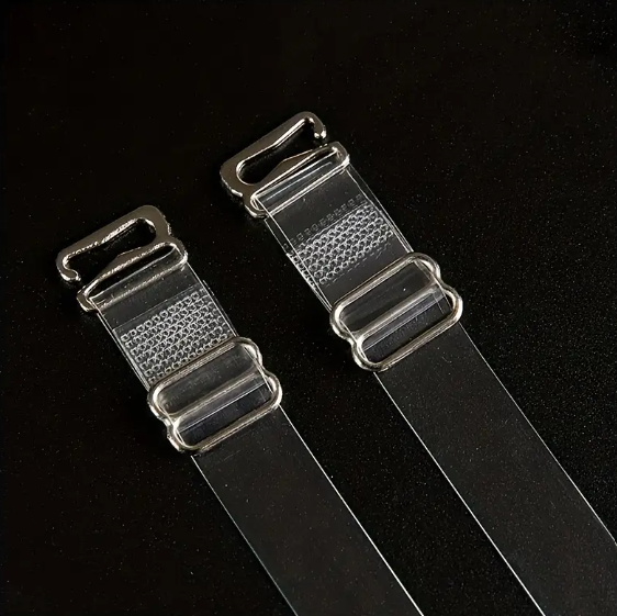 Close-up of two adjustable, transparent clear bra straps with silver-toned metal clasps and adjusters on a dark background.