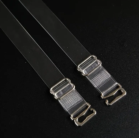 Close-up of two adjustable, transparent clear bra straps with silver-toned metal clasps and adjusters on a dark background.