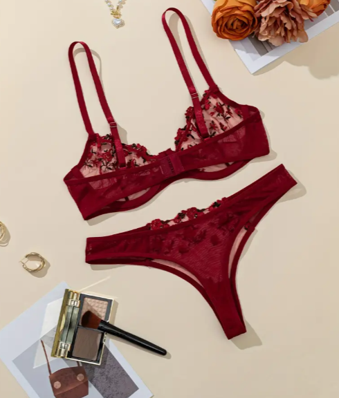 Red lingerie set with floral details on a beige surface.