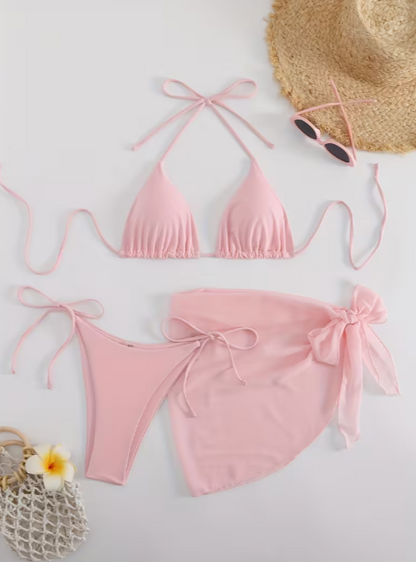 Pink bikini set with a straw hat, sunglasses, and flower on a light background