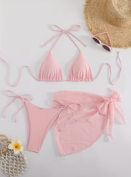 Pink bikini set with a straw hat, sunglasses, and flower on a light background