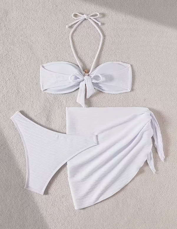 White three-piece bikini set for women featuring a starfish embellishment, halter neck bandeau top, matching bikini bottom, and wrap cover-up skirt – chic beachwear from The Seventh Muse.