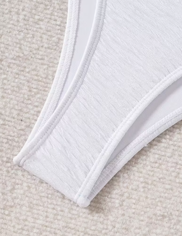 White three-piece bikini set for women featuring a starfish embellishment, halter neck bandeau top, matching bikini bottom, and wrap cover-up skirt – chic beachwear from The Seventh Muse.