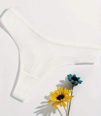 A set of four cotton panties in black, white, beige, and blue colors, displayed on a soft, textured surface.
