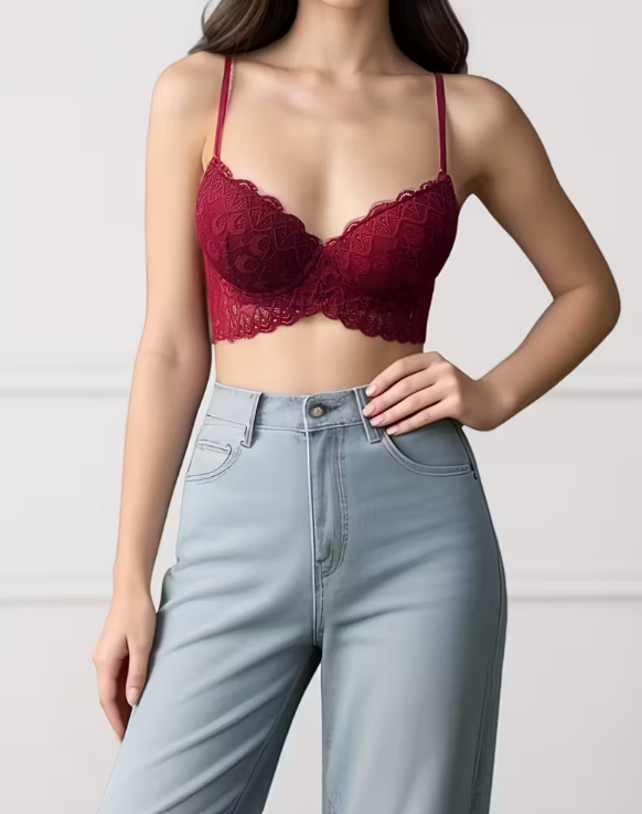 Person wearing a red lace bralette and light blue jeans on a plain background