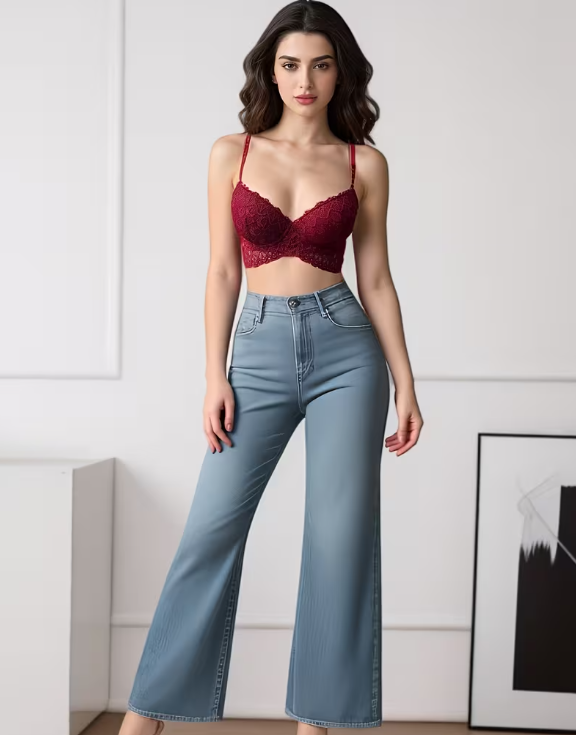 Woman wearing a red bralette and blue jeans against a white wall.