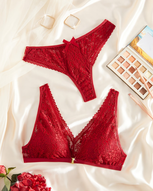 Red lace lingerie set on a white fabric background with makeup products.
